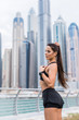 © F8  \ Suport Ukraine - Strong fit female athlete getting ready for workout towards the skyscrapers. Strong fitness woman tying ponytail. Motivation and healthy lifestyle concept.