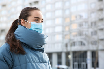 Woman wearing disposable mask outdoors. Dangerous virus