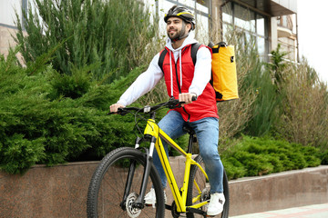 Poster - Courier with thermo bag riding bicycle outdoors. Food delivery service