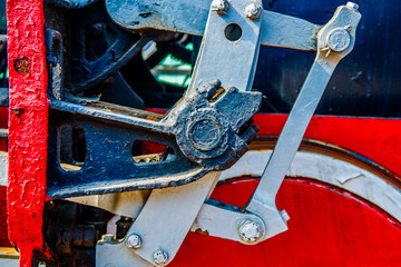 Metal parts and details of driving wheels of a vintage steam engine locomotive. Closeup view. Abstract art of coal and iron machinery. The history of railway transport.