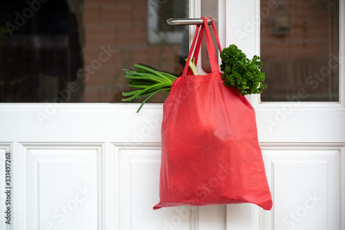 Fotomural Shopping bag with goods and food is hanging at the front door, neighborhood help