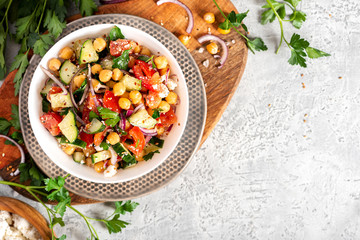 Sticker - Chickpea salad with tomatoes, cucumber, feta cheese, parsley, onions and lemon in a plate on a concrete background top view, copy space. Healthy vegetarian food, oriental and Mediterranean cuisine.