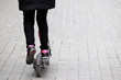© Oleg - Girl rides an electric scooter on a city street, legs in sneakers on a sidewalk. Riding e-scooter in spring