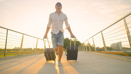 LOW ANGLE: Male tourist late to airport runs across an overpass with luggage