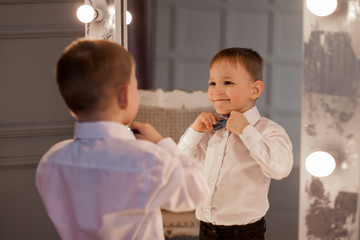 cute little boy posing in front of mirror indoors