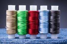Several Spools Of Colored Thread For Sewing On Denim. Concept Needlework And Tailoring.