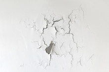 Crack On The Wall. Old Paint On A White Background Collapses Under The Influence Of Time.