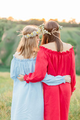 Young women relaxing and enjoying sunset in spring. Happy beautiful girls on the nature picnic.