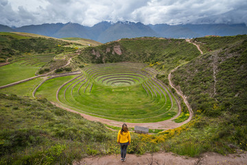 Female traveller at the circular Inca Terraces at Moray in the Sacred Valley of the Incas, Cusco Region, Peru.