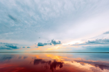 Wall Mural - pink lake and sandy beach with a sea bay under a blue sky with clouds