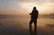 angler catching fish in the lake during hazy sunrise
