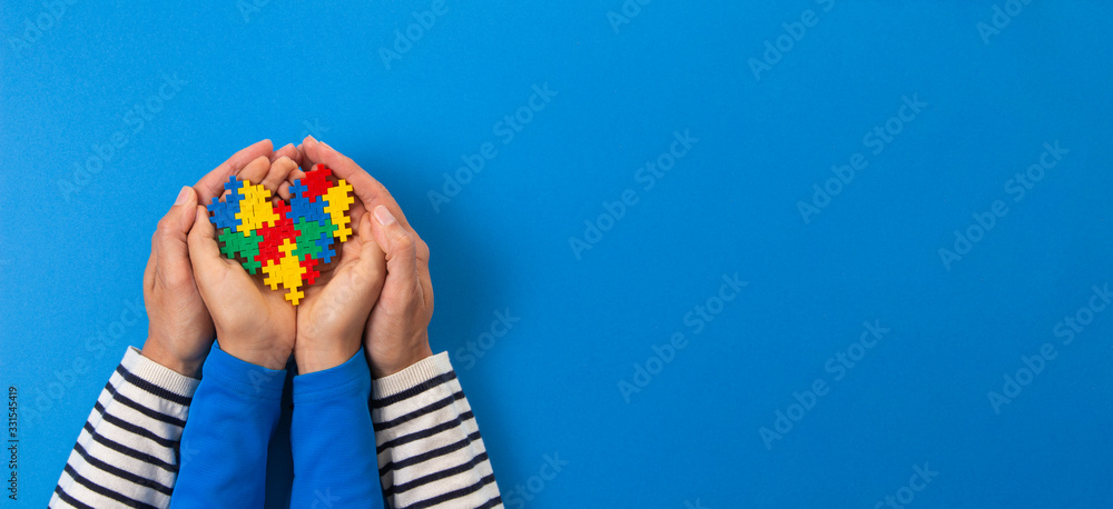 World autism awareness day concept. Adult and child hands holding puzzle heart on light blue background - obrazy, fototapety, plakaty 
