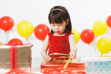 Wall Mural - toddler girl unpacking birthday gift box on her birthday party