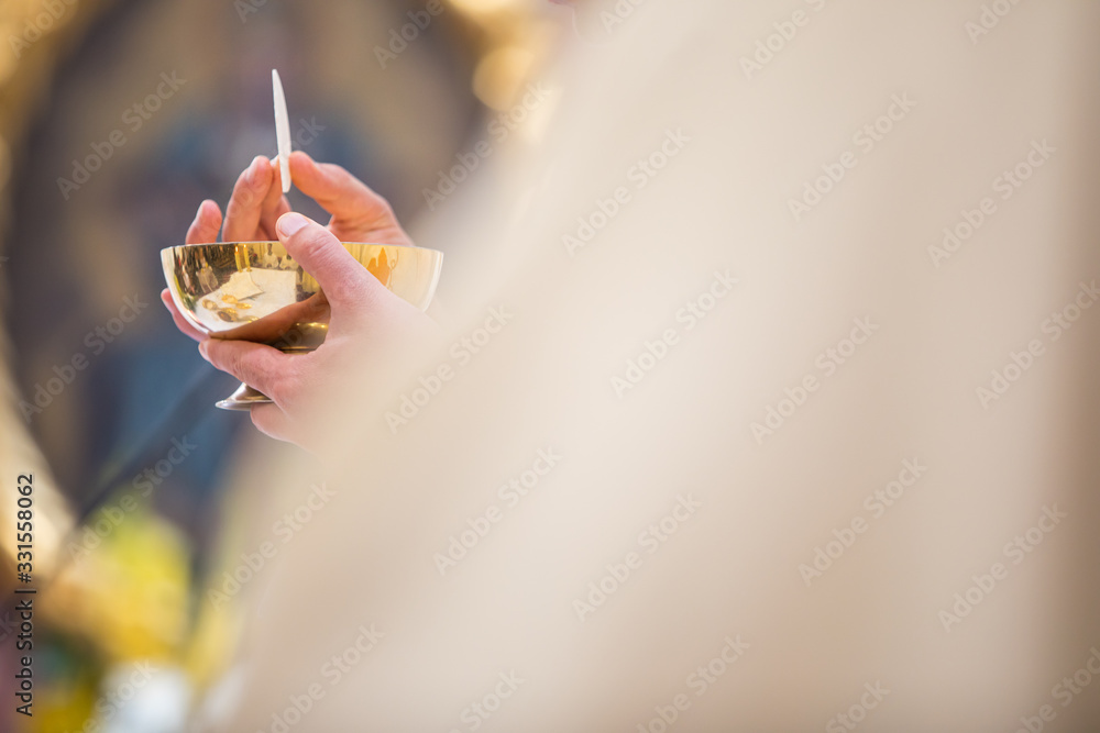 Priest' hands during a wedding ceremony/nuptial mass (shallow DOF; color toned image) - obrazy, fototapety, plakaty 