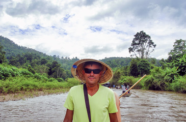 Poster - Man weearing straw hat on a river excursion in East Asia