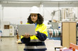 © Mangostar - Focused female technician using laptop at printing house. Concentrated factory employee standing with open laptop at workplace. Print manufacturing concept