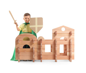 Wall Mural - Little boy dressed as knight playing with take-apart house on white background