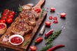 © chernikovatv - Fresh delicious juicy steak on the bones with vegetables and spices against a dark background