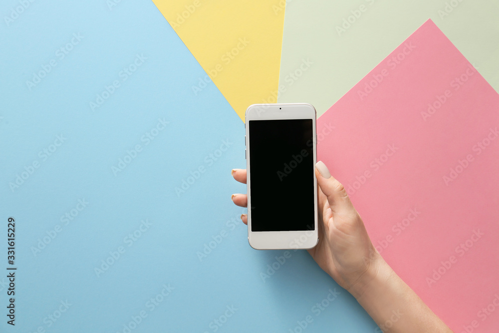 Female hand with mobile phone on color background