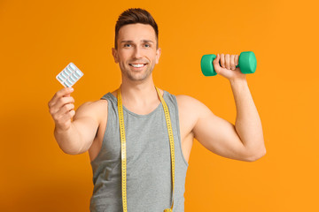 Sticker - Young man with weight loss pills, measuring tape and dumbbell on color background