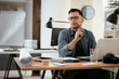 © JustLife - Designer in office. Businessman working on new architect project.