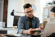 © JustLife - Designer in office. Businessman working on new architect project.