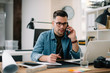 © JustLife - Businessman in office. Handsome man talking on phone at work.