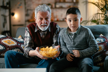 Grandfather and grandson watching television. Grandfather and grandson enjoying at home.