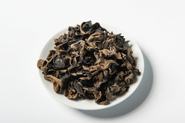 Wall Mural - Dried agaric is isolated in a wooden bowl on a white background. Tile (top) driven fengus