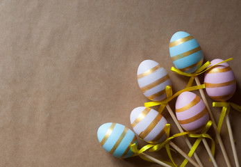 Multicolored Easter painted eggs with decorative stripes and yellow ribbons lie on a craft background . The Concept Of Easter