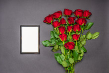 Bouquet Of Fresh Red Rose Flowers And Empty Photoframe On Black Background. Floral Composition, Mourning Card For Event, Mock Up. Mourning, Condolence, Commemoration Concept. Flat Lay, Top View