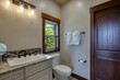 © Iriana Shiyan - New luxury bathrooms with rich color wooden doors, natural beige countertops, white cabinets and sinks. Bright clean grey walls and floor.