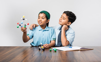 Indian school boy and girl or science student in uniform Using Molecular Model Kit for studying physics, selective focus