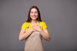 © LumenSt - Young woman in an apron on a gray background.