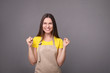 © LumenSt - Young woman in an apron on a gray background.