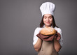 © LumenSt - Young woman in an apron with fresh bread on gray background. Cook concept