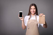 © LumenSt - .Young woman in apron with coffee on  gray background. Barista concept