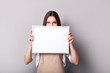 © LumenSt - Young woman in  apron holding sign on  gray background.