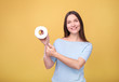© LumenSt - Young woman holds toilet paper on  yellow background.
