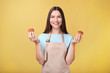 © LumenSt - Young woman in apron with cupcakes on a yellow background
