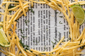 Canvas Print - top view of crispy french fries, sliced lime and dill on newspaper