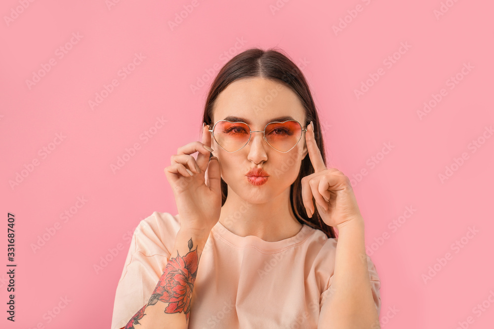 Young woman with stylish sunglasses on color background