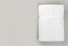 Top View Of Folded Clean White Bathroom Towel On Gray Background With Copy Space