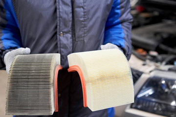 New and old dirty automotive engine air filter in the hands of an auto mechanic. Auto repair concept.