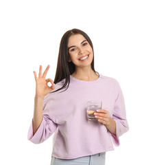 Canvas Print - Beautiful young woman with glass of water showing OK on white background