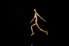 Wooden Doll Imitating Running On Black