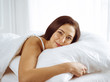 © rogerphoto - Beautiful young brunette woman sleeping while lying in bed comfortably and blissfully. Good morning concept