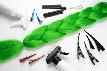 Wall Mural - Kanekalon artificial hair of a bright green color for braiding braids, lying on a white background next to accessories for braiding braids