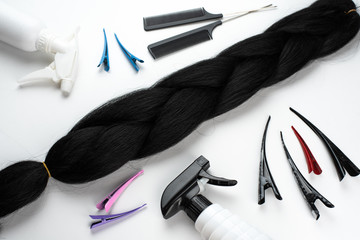 Wall Mural - Kanekalon artificial black hair for braiding braids, lying on a white background next to the accessories for braiding braids