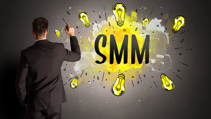 businessman drawing colorful light bulb with SMM abbreviation, new technology idea concept